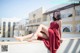 A woman in a red dress sitting on a ledge.