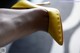 A close up of a person's hand holding a pair of yellow shoes.