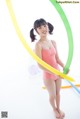 A young woman in a pink bathing suit holding a hula hoop.