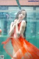 A woman in a red dress is standing in the water.