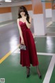 A woman in a red dress standing in a parking garage.