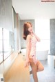 A woman in a pink dress posing in a bathroom.