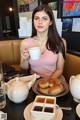 A woman sitting at a table with a cup of coffee.