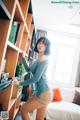 A woman standing in front of a bookshelf in a living room.