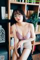 a woman sitting on top of a chair next to a book shelf