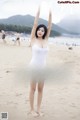 A woman in a white bathing suit standing on a beach.