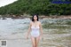 A woman in a white bathing suit standing in the water.