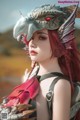 A woman with red hair wearing a dragon headpiece.