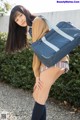 A young woman in a school uniform holding a blue bag.