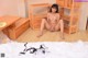 A naked asian woman sitting on a bed in a room.