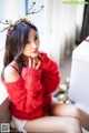 A woman in a red sweater sitting on a window sill.