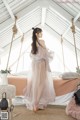 a woman in a white polka dot dress standing on a swing