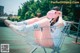 A woman sitting in a shopping cart with a pink mask on.