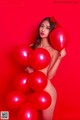 A naked woman holding a bunch of red balloons.