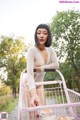 A woman in a white bodysuit pushing a pink shopping cart.