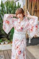 A woman wearing a white kimono standing on a wooden deck.