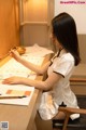 A woman sitting at a table writing on a piece of paper.