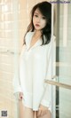 A woman in a white shirt standing in a bathroom.