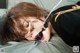 A woman laying on a bed with a rope around her mouth.