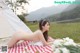 A naked woman laying on a picnic blanket in a field.