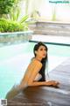 A woman in a white dress sitting by a swimming pool.