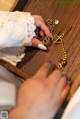 A woman's hand holding a gold chain on a wooden table.