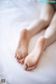 A close up of a person's bare feet on a bed.