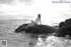 A woman sitting on a rock in the ocean.