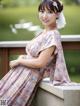 A woman in a pink dress sitting on a wooden bench.