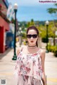 A woman wearing sunglasses standing on a sidewalk.