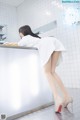 A woman in a white shirt and high heels leaning on a counter.