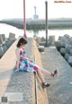 A woman sitting on a concrete wall by the water.