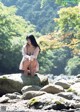 A woman sitting on a rock in the middle of a river.