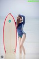 A woman standing in the water holding a surfboard.