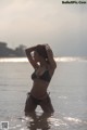 A woman in a black bikini standing in the water.