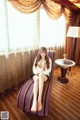 A woman sitting on a purple chair in a hotel room.