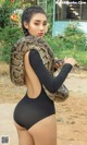 A woman in a black bodysuit holding a large snake.