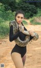 A woman in a black bodysuit holding a large snake.