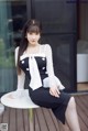 A woman sitting on top of a white table.