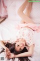 A woman laying on a bed in a pink dress.