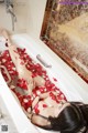 A woman laying in a bathtub filled with rose petals.