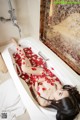 A woman laying in a bathtub filled with rose petals.