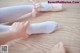 A person tying up a pair of ballet shoes on a wooden floor.