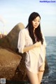 A woman standing on a rock by the ocean.