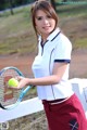 A woman holding a tennis racket and a tennis ball.