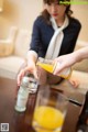 A woman pouring orange juice into a glass on a table.