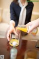 A woman pouring orange juice into a glass on a table.