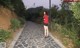 A woman in a red shirt and black skirt walking down a path.