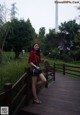 A woman standing on a wooden bridge in a park.