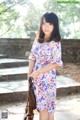 A woman in a floral dress is posing for a picture.